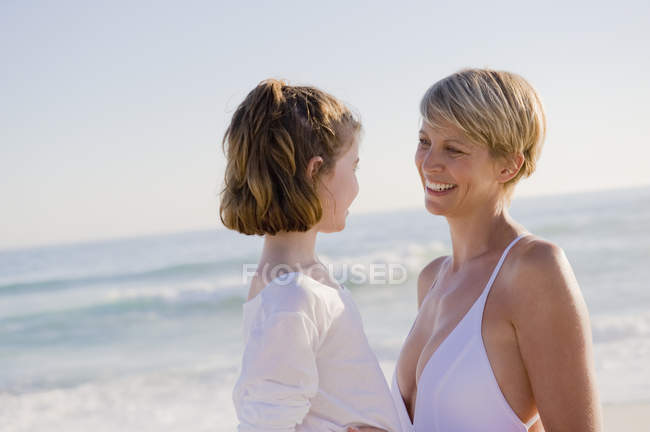 Mujer con hija disfrutando de vacaciones en la playa - foto de stock