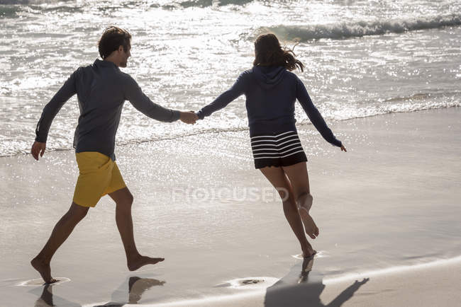 Happy cheerful young couple having on summer beach — Stock Photo