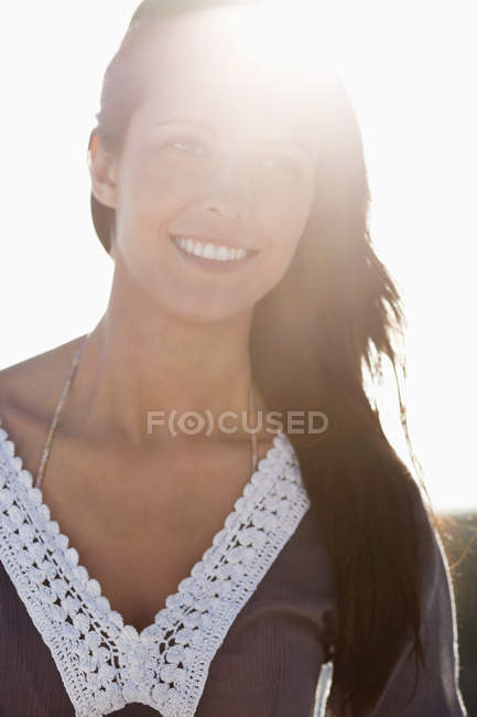 Close-up of brunette woman smiling in backlit — Stock Photo
