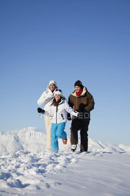 Пара і дочка в лижному одязі біжать у снігу — стокове фото