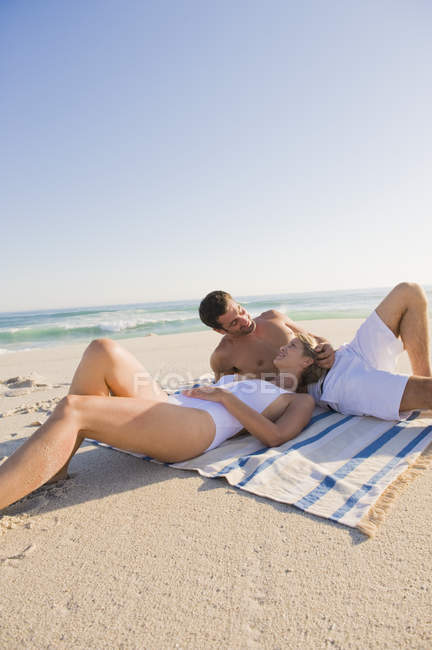 Pareja de risa relajada descansando en la playa de arena - foto de stock