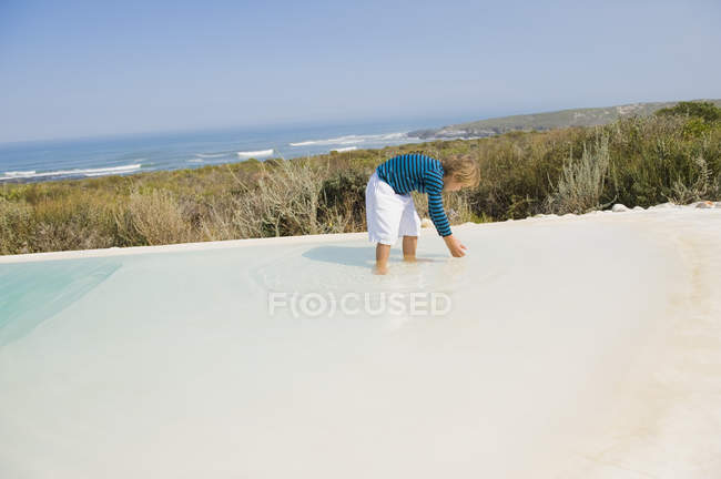 Menino brincando na piscina infinita na costa do mar — Fotografia de Stock