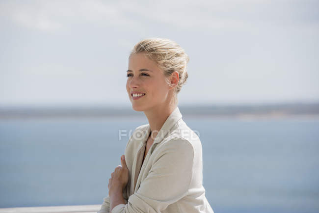 Счастливая элегантная молодая женщина смотрит в сторону озера — стоковое фото
