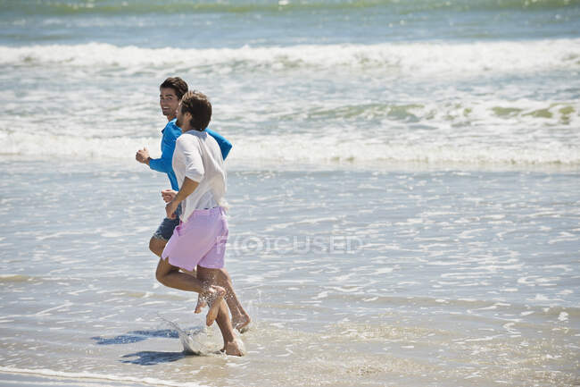 Two men running on the beach — Stock Photo