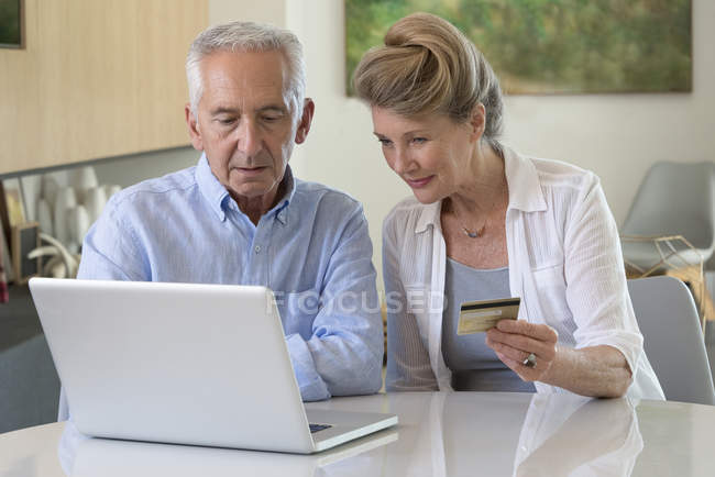 Senior couple shopping en ligne avec ordinateur portable à la maison — Photo de stock
