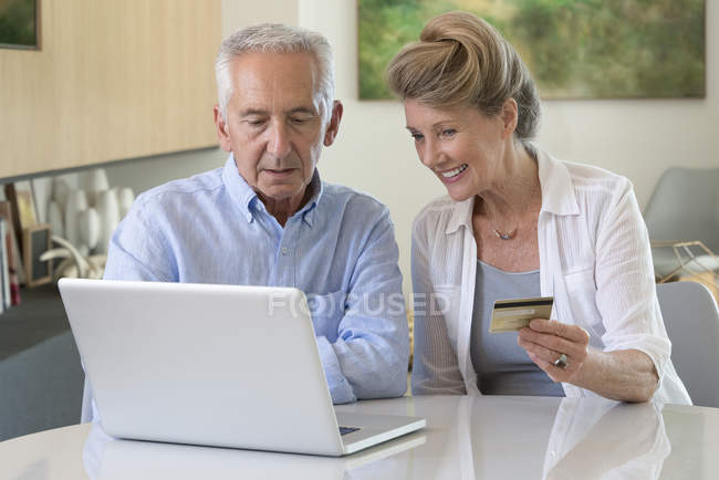 Coppia senior shopping online con laptop a casa — Foto stock