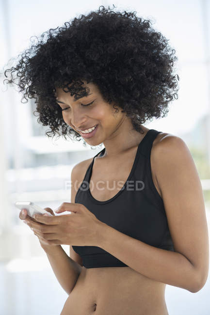 Femme souriante dans le sport noir message texte haut avec téléphone mobile — Photo de stock
