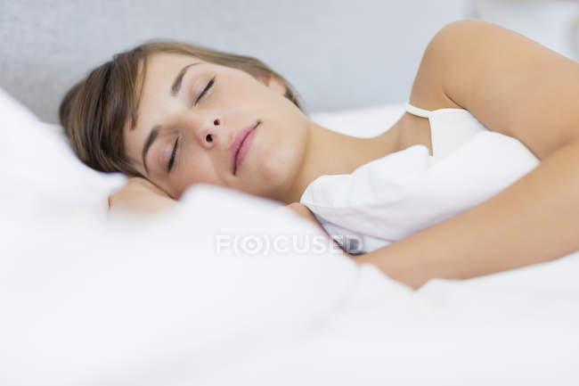 Nahaufnahme einer ruhigen jungen Frau, die auf dem Bett schläft — Stockfoto