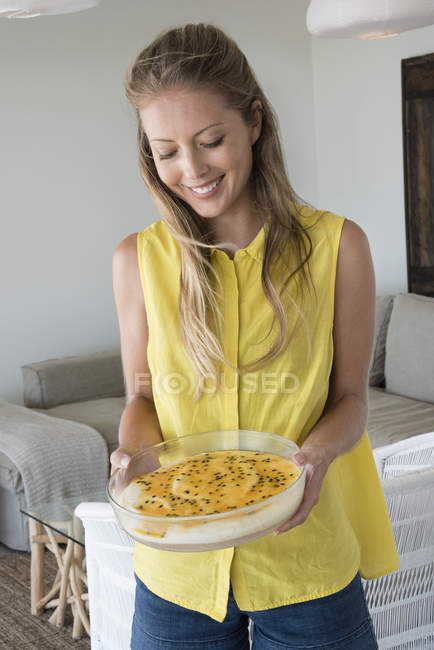 Улыбающаяся элегантная женщина держит чизкейк в гостиной — стоковое фото