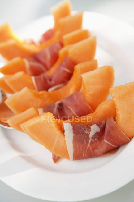 Slices of muskmelon wrapped in ham — Stock Photo