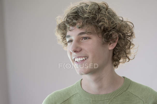 Retrato de adolescente sorridente com cabelo encaracolado em fundo cinza — Fotografia de Stock