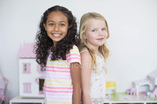 Retrato de niñas sonrientes de pie juntas - foto de stock