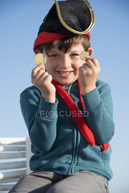 Піратський хлопчик, що показує монети на блакитному небі — стокове фото