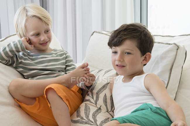 Dois meninos felizes sentados no sofá na sala de estar — Fotografia de Stock