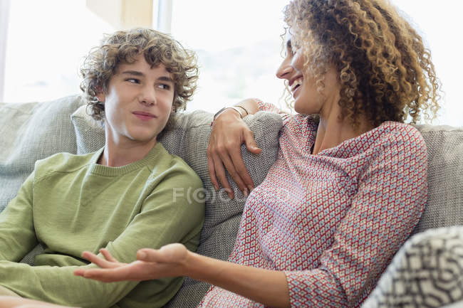 Щаслива мати і син розмовляють на дивані у вітальні — стокове фото