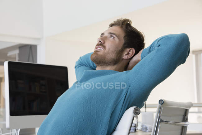 Junger verträumter Mann entspannt sich im Büro — Stockfoto