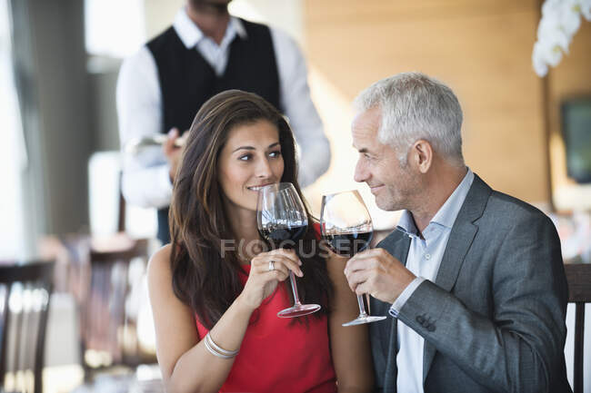 Pareja disfrutando del vino tinto en un restaurante - foto de stock