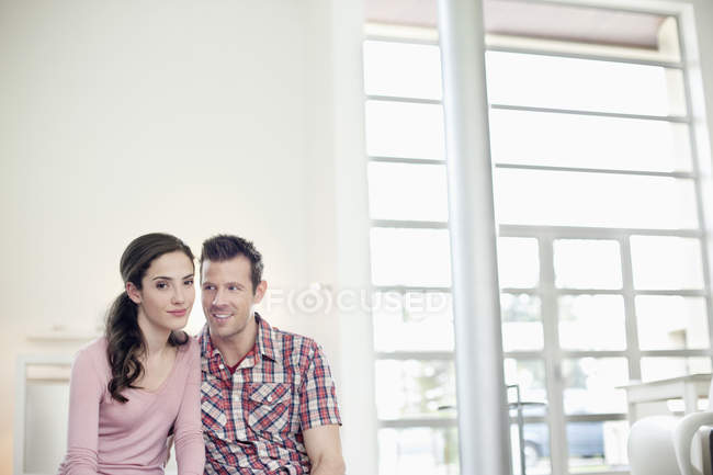 Портрет улыбающейся романтической пары, сидящей дома — стоковое фото