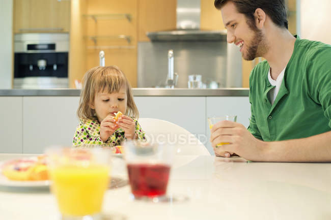 Homem e filha tomando café da manhã à mesa em casa — Fotografia de Stock