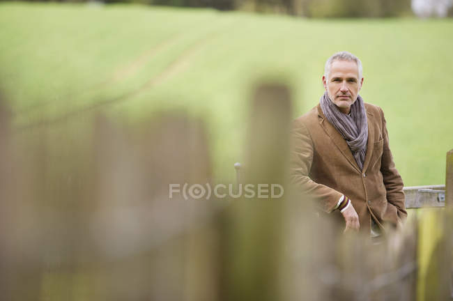 Eleganter älterer Mann lehnt an Zaun im Feld — Stockfoto