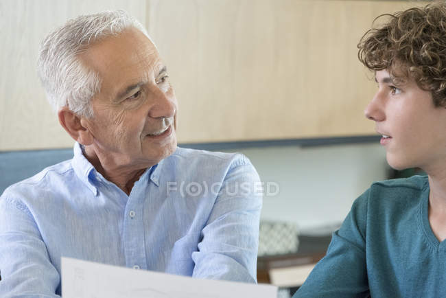Senior erledigt Papierkram mit Enkel im Wohnzimmer — Stockfoto