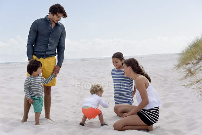 Feliz familia joven disfrutando en la playa - foto de stock