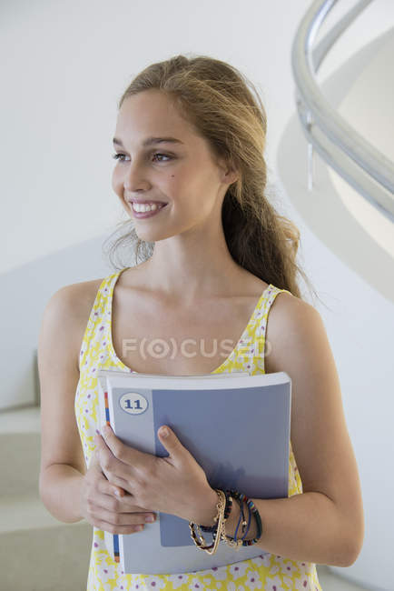 Heureuse adolescente tenant des livres dans les escaliers — Photo de stock