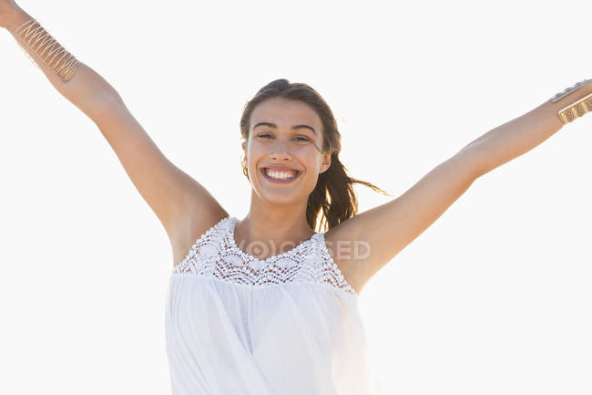 Portrait of happy young woman standing on white background with hands up — Stock Photo