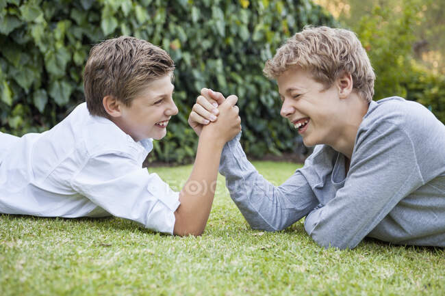 Два мальчика армрестлинг на траве — стоковое фото