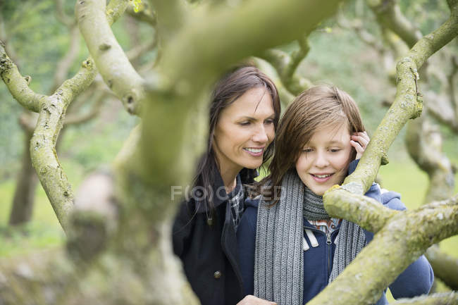 Mulher com filha adolescente olhando para galho de árvore no pomar — Fotografia de Stock
