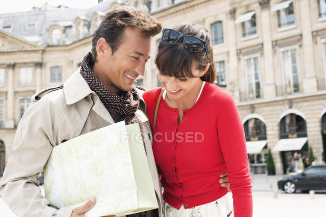 Sonriente pareja caminando por la calle con bolsa de compras, París, Ile-de-France, Francia - foto de stock