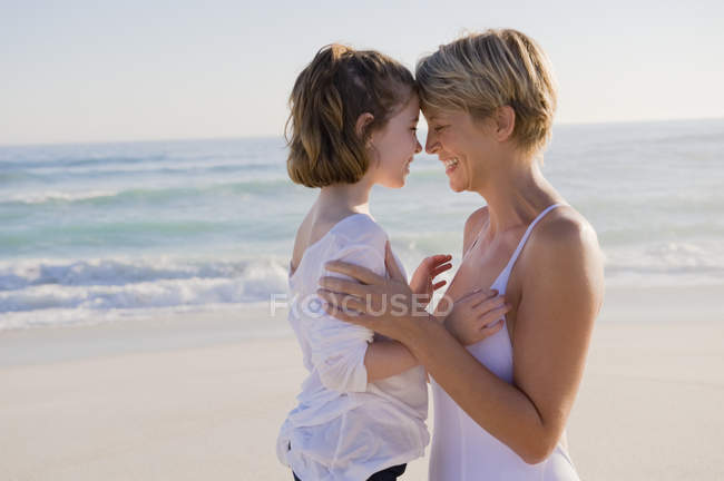 Woman with daughter rubbing noses on beach — Stock Photo