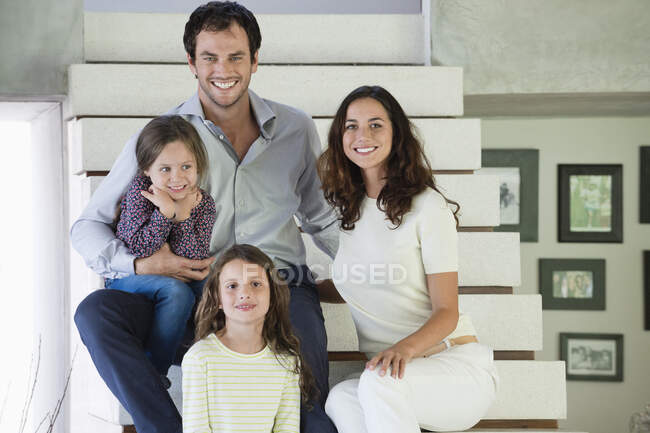 Family sitting on steps and smiling — Stock Photo