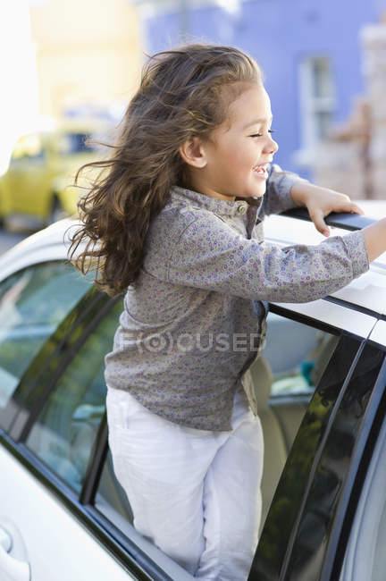 Cute little girl looking out of car window on street — Stock Photo