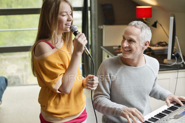 Homme jouant du piano avec sa fille chantant — Photo de stock