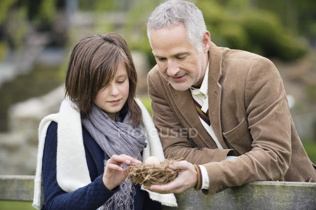 Uomo con figlia che tiene nido d'uccello nel parco — Foto stock