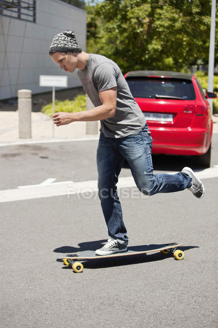 Jovem homem focado skate na estrada — Fotografia de Stock