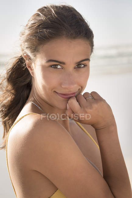 Jovem sorrindo mulher olhando para a câmera na praia — Fotografia de Stock