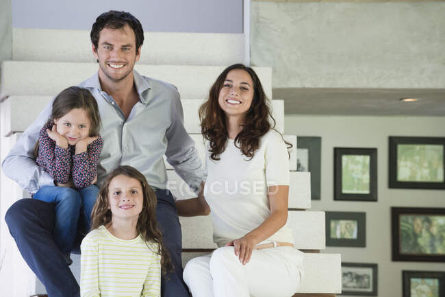Family sitting on steps and smiling — Stock Photo