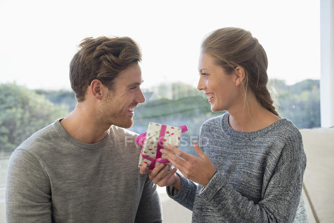 Счастливая пара с подарком на день рождения смотрят друг на друга — стоковое фото