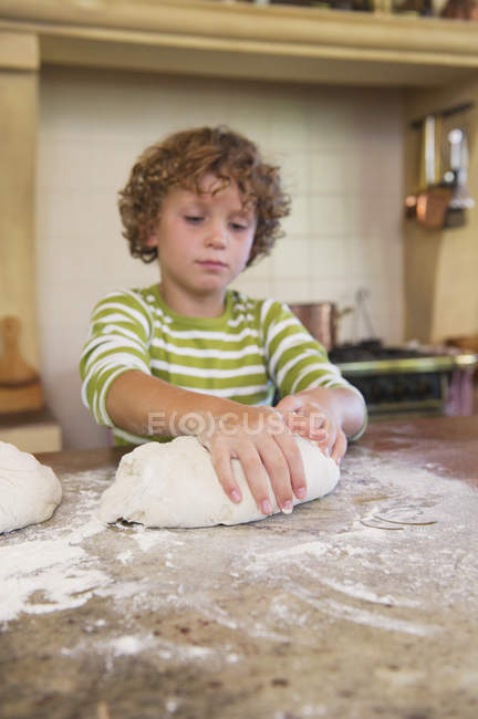 Mignon petit garçon pétrissant la pâte dans la cuisine — Photo de stock