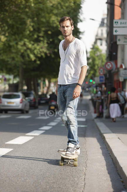 Человек катается на скейтборде по дороге на городской улице — стоковое фото