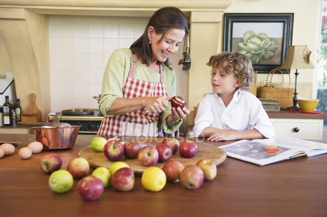 Бабушка и маленький мальчик чистят фрукты дома — стоковое фото
