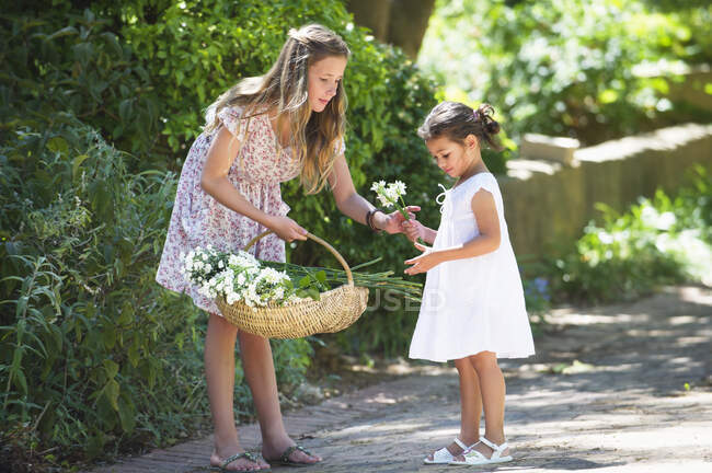 Chica dando flor a su hermana pequeña - foto de stock