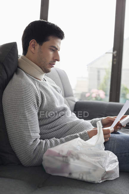Uomo seduto sul divano e la lettura di prescrizione medica — Foto stock