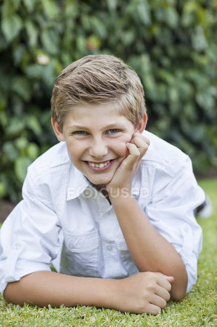 Portrait of smiling teenage boy lying on grass — Stock Photo