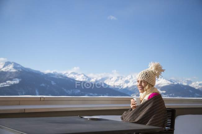 Mulher sentada com xícara de café no terraço com vista para as montanhas, Crans-Montana, Alpes Suíços, Suíça — Fotografia de Stock