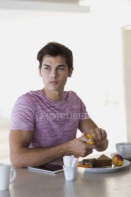 Réfléchi jeune homme prenant le petit déjeuner à la maison — Photo de stock