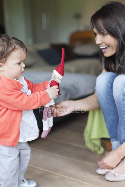 Женщина смотрит на свою внучку, играющую с игрушкой — стоковое фото