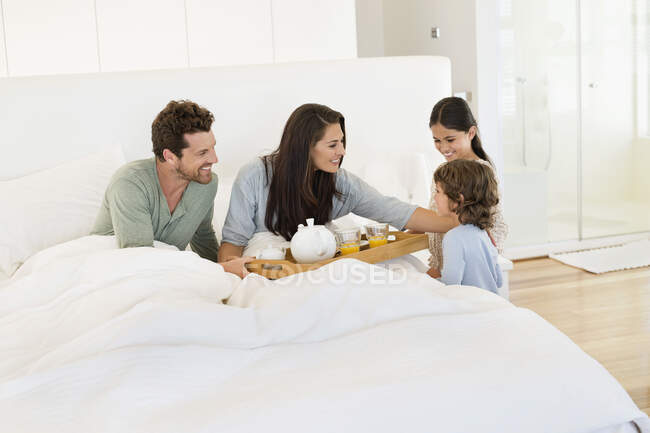 Niños sirviendo té a sus padres en la cama - foto de stock